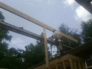 Carpenter setting a ridge beam over a new addition frame — Ice Dam Removal by Roofing Brothers in Greenback