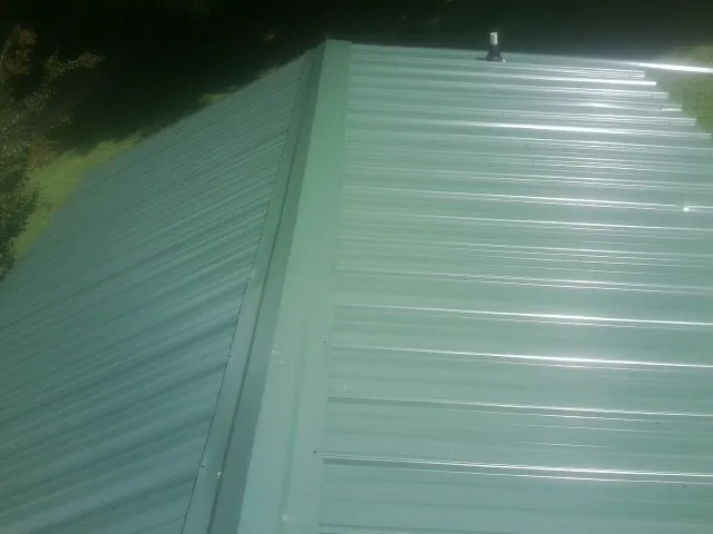 New green metal panels meeting at the ridge of a roof — Flat Roof Repair work by our crew in Greenback