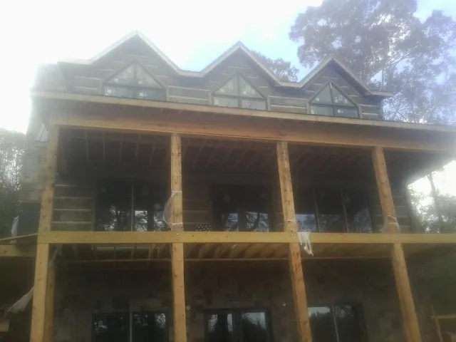 Dormers and porch framing on a large log home under construction — Roof Coating work by our crew in Greenback