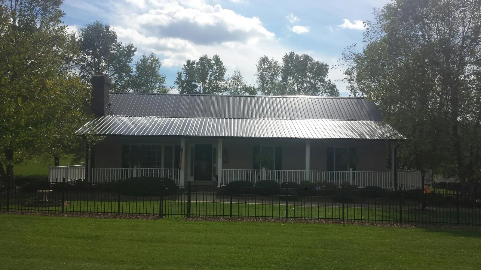 Gray metal roof on a brick ranch with a full width front porch — Gutter Guard Installation work by our crew in Greenback