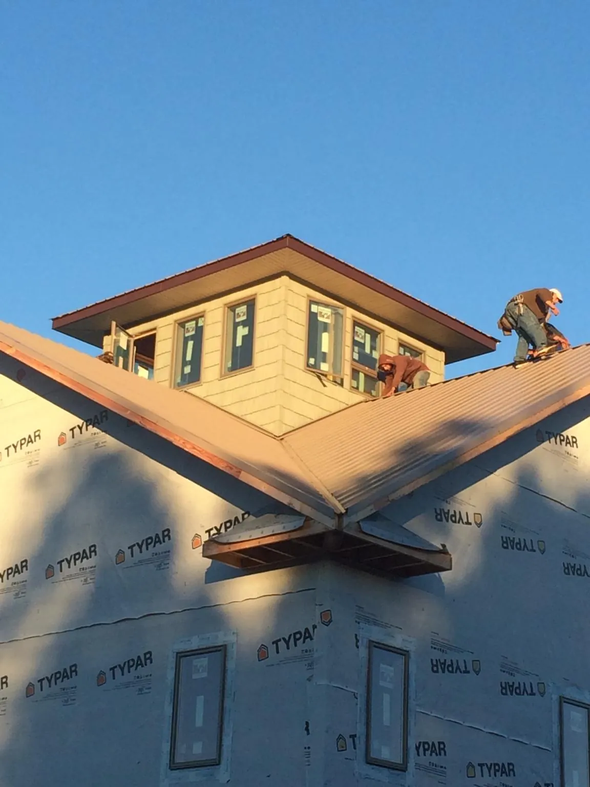 Roofers working around a rooftop cupola on a new metal roof at sunset — Roof Waterproofing in Greenback by Roofing Brothers